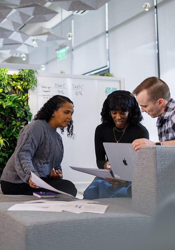 Employees collaborating and reviewing print-outs together in an Exact Sciences office.